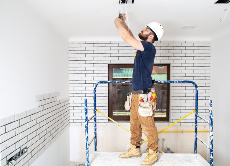 Remodeling electrician updating the electrical wiring for new lamps in a kitchen undergoing renovation