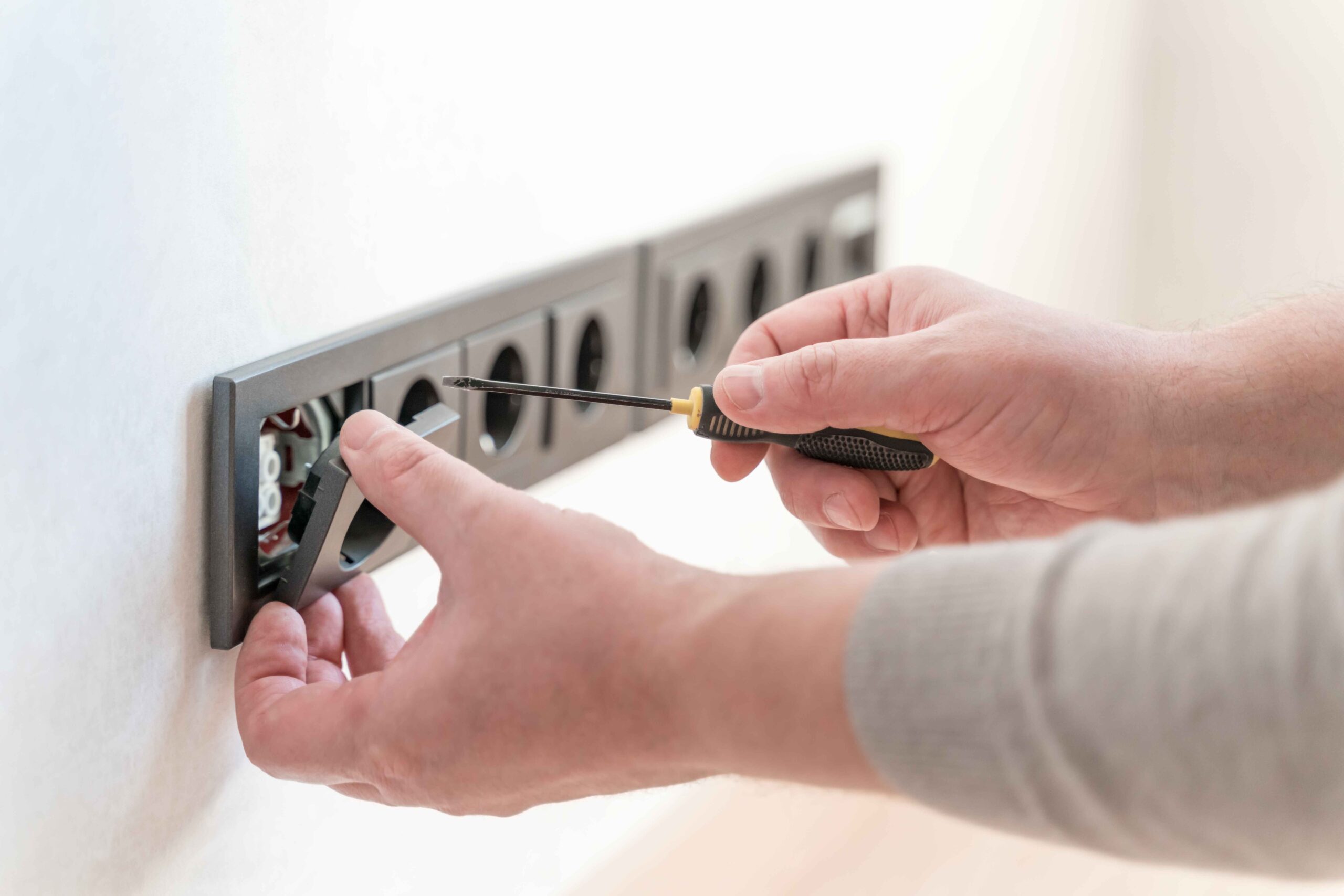 electrician installs sockets in the wall of a new