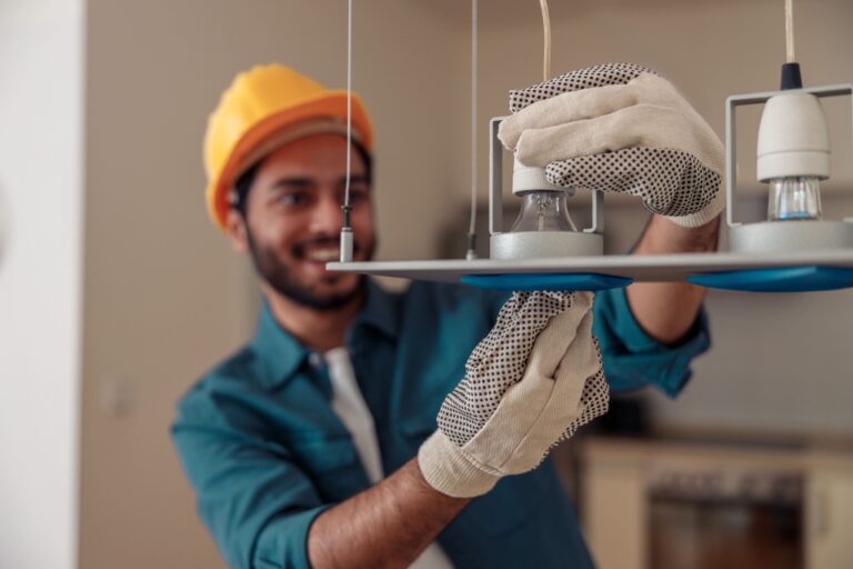 Electrician installing a modern light fixture in a residential home.